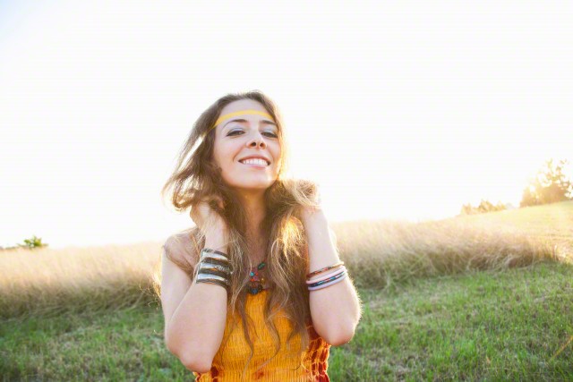 Portrait of mid adult woman wearing hippy clothing, standing in field, smiling